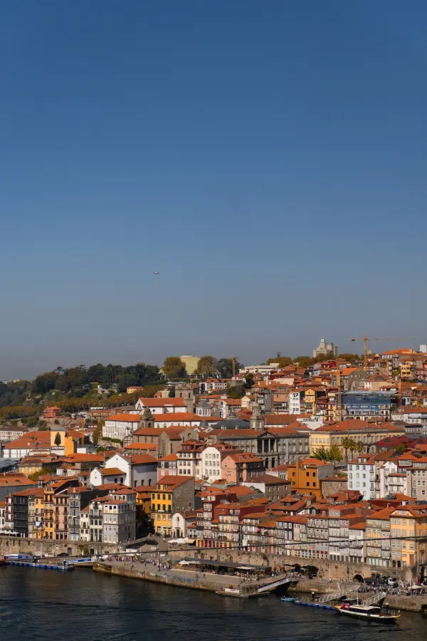 Vista do Porto sobre o rio Douro, com casas de telhado laranja a descer até à água.